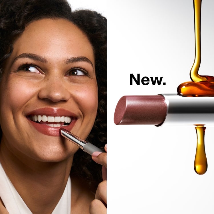 Smiling, curly brunette haired model applying new Almost Lipstick in Nude Honey to lips, in a brightly lit setting